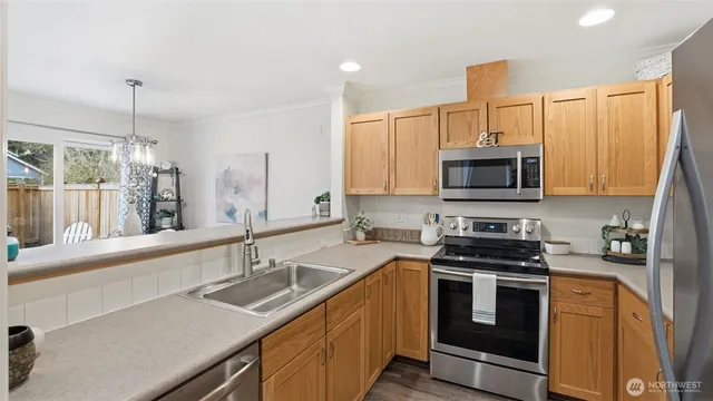 a kitchen with stainless steel appliances a sink a stove a microwave and wooden cabinets
