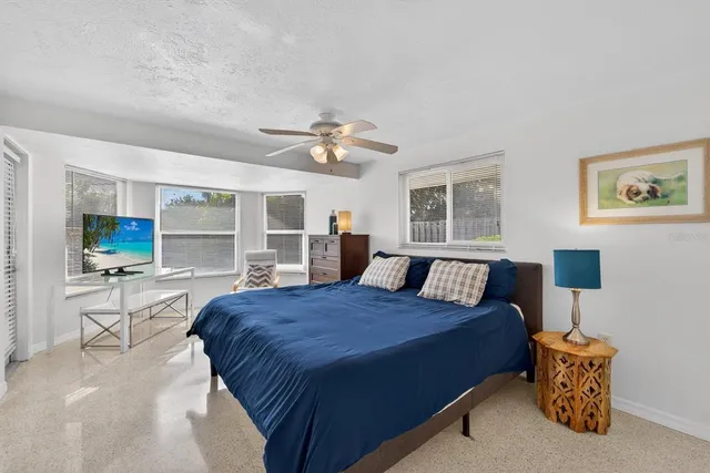 a spacious bedroom with a large bed a chandelier and windows