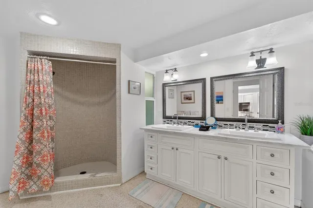 a bathroom with a double vanity sink mirror and shower