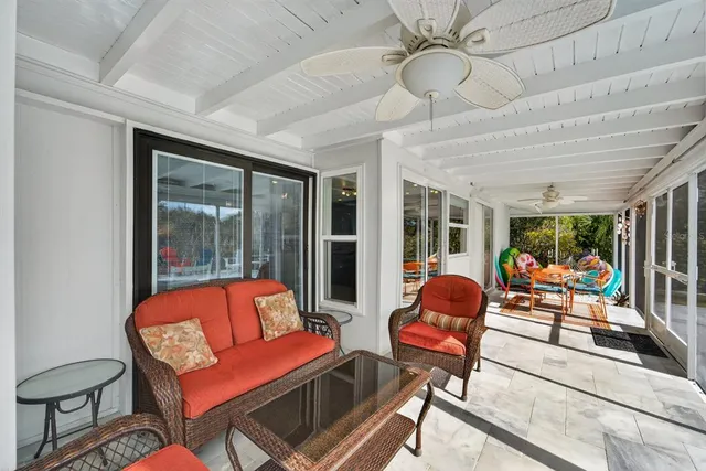 a living room with furniture a ceiling fan and a large window