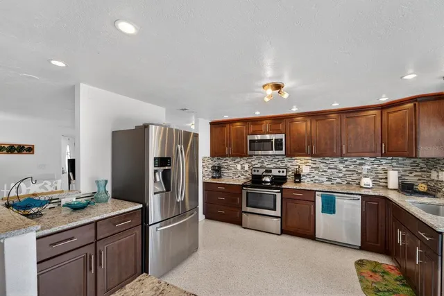 a kitchen with stainless steel appliances granite countertop a stove refrigerator sink and microwave