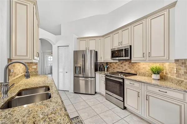 a kitchen with granite countertop a refrigerator sink and stove