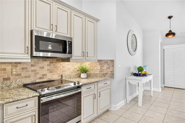 a kitchen with stainless steel appliances granite countertop white cabinets a stove a sink and a microwave