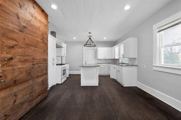 a kitchen with cabinets wooden floor and a view of kitchen
