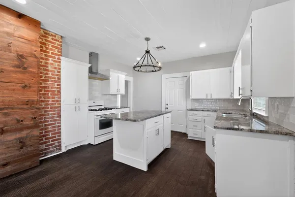 a kitchen with granite countertop a sink cabinets and wooden floor