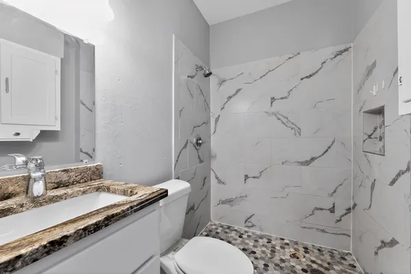 a bathroom with a granite countertop sink toilet and shower