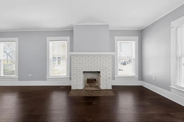 an empty room with wooden floor fireplace and windows