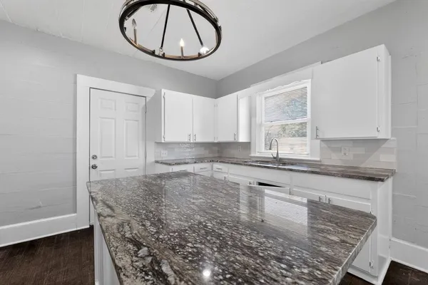 a kitchen with granite countertop a sink a stove and cabinets