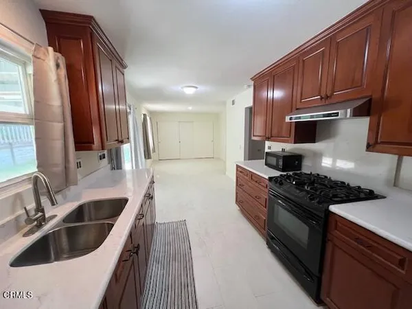 a kitchen with granite countertop a sink stainless steel appliances wooden cabinets and a window