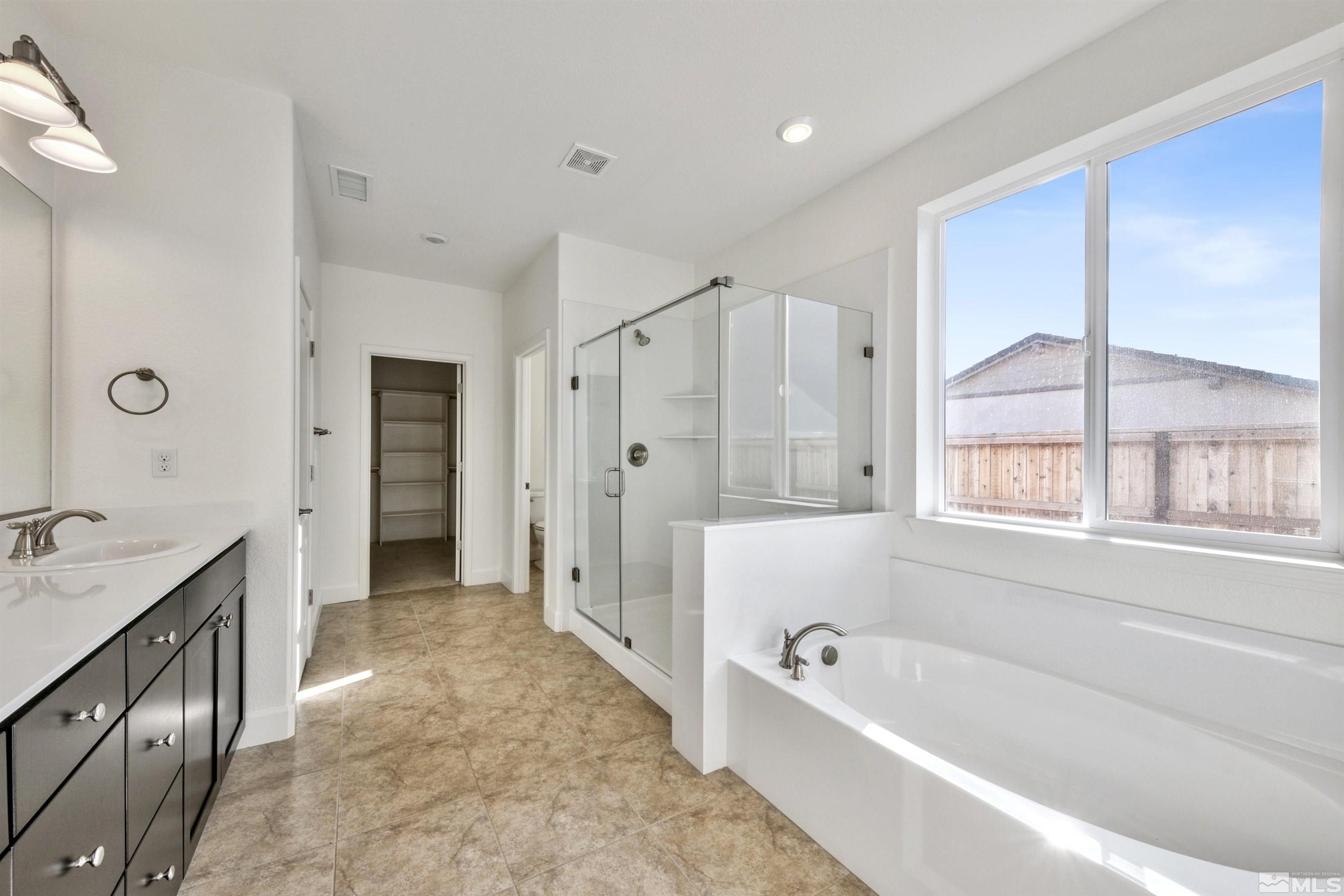 4505 High Pointe Drive Reno, NV 89521 - Photo 23 of 30 a bathroom with a bathtub a double vanity sink a vanity a window and a shower