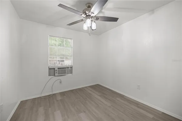 an empty room with a chandelier fan and windows
