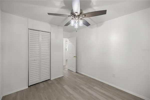 an empty room with wooden floor and fan