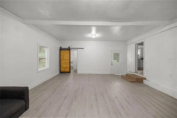 a view of an empty room with window and wooden floor