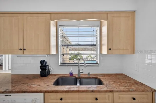 a kitchen with granite countertop a sink a window and cabinets