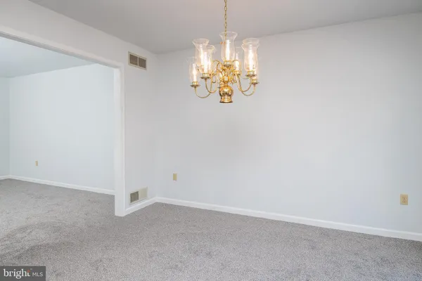 a view of an empty room with chandelier fan