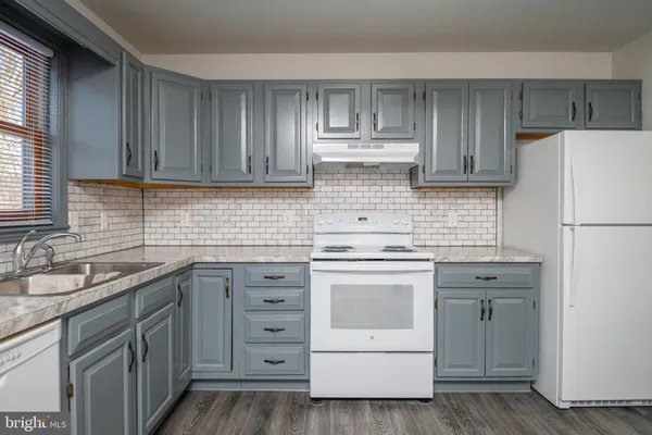 a kitchen with cabinets appliances a sink and a window