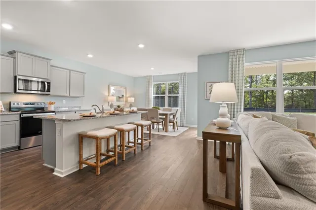 a living room with stainless steel appliances granite countertop furniture a fireplace a flat screen tv and a kitchen view