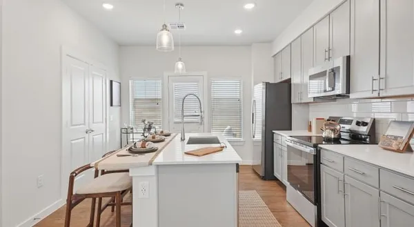 a kitchen with stainless steel appliances a sink a stove a refrigerator cabinets and living room view