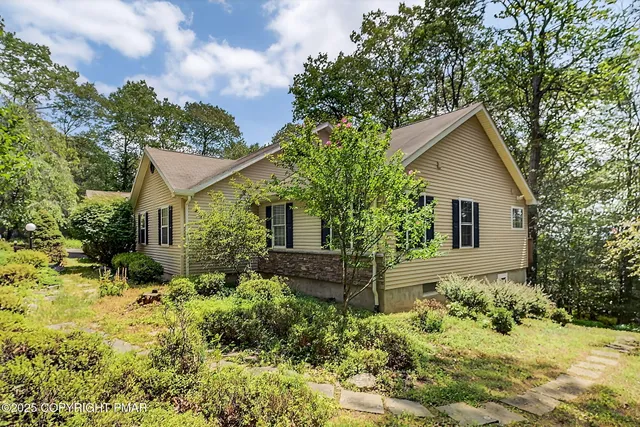a view of a house with a street and large trees