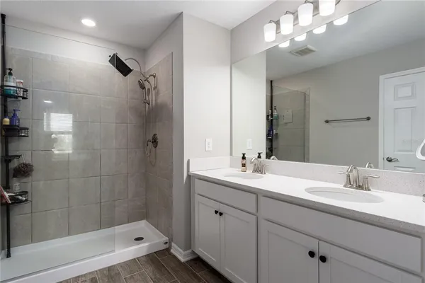 a bathroom with a double vanity sink a large mirror and shower