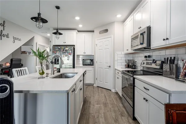 a kitchen with stainless steel appliances kitchen island granite countertop a sink a stove a refrigerator and cabinets