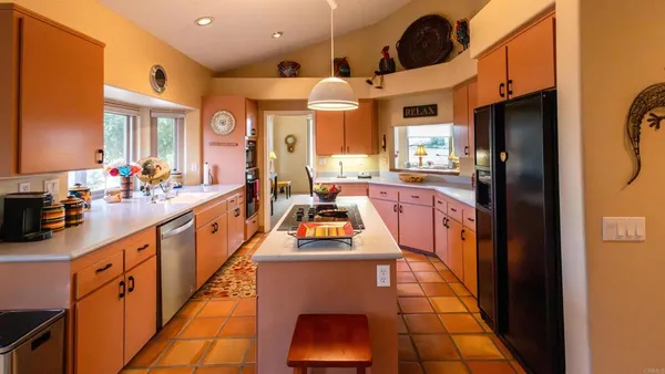 a kitchen with stainless steel appliances granite countertop a refrigerator a sink dishwasher a dining table and chairs with wooden floor