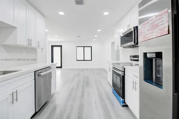 a large kitchen with stainless steel appliances granite countertop a lot of cabinets and wooden floor