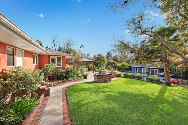 a backyard of a house with table and chairs plants and large trees