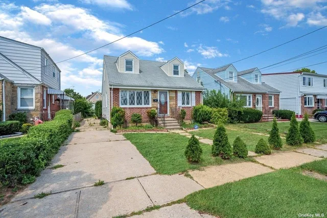 a front view of a house with a yard and potted plants