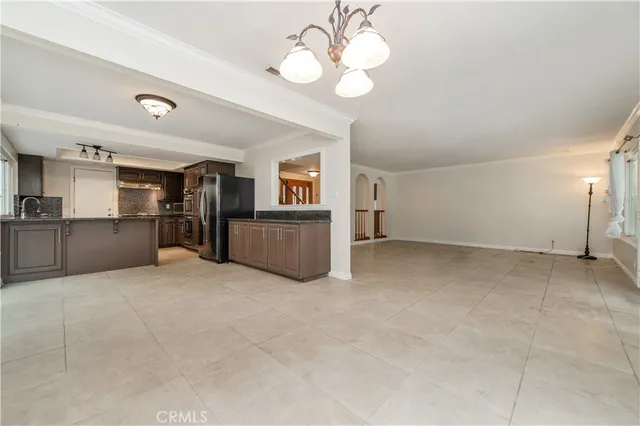 a view of a kitchen with a sink cabinet an empty room and chandelier fan