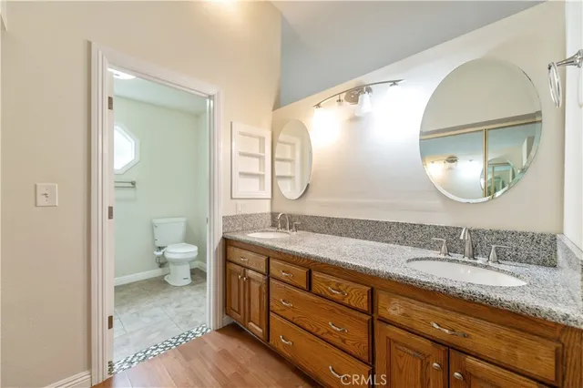 a spacious bathroom with a granite countertop toilet a sink and a mirror