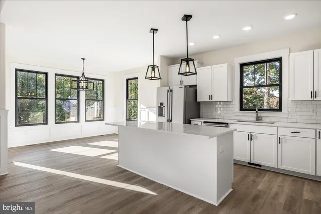 a open kitchen with stainless steel appliances granite countertop a stove a sink a center island a refrigerator and a wooden floor