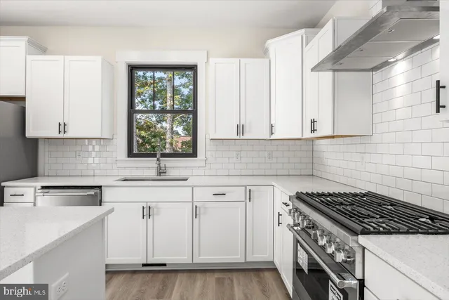 a kitchen with white cabinets appliances a sink and a window