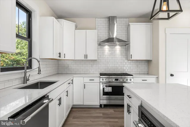 a kitchen with stainless steel appliances white cabinets and a stove top oven