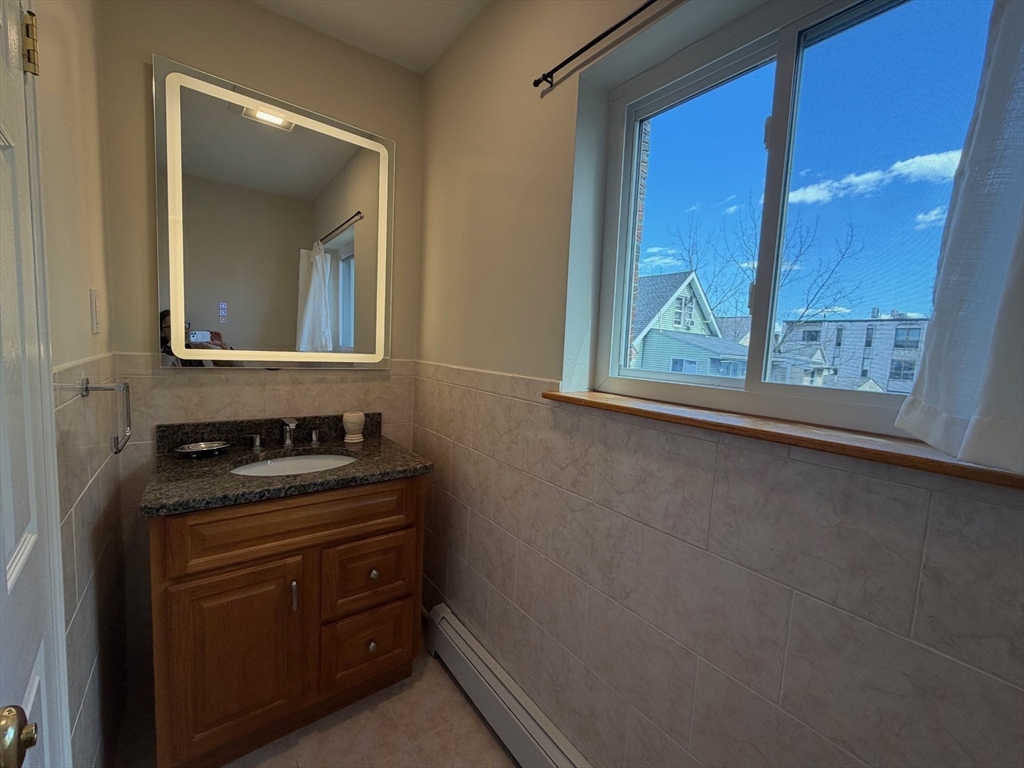 383 Langley Road, Unit 11 Newton, MA 02459 - Photo 11 of 15 a bathroom with a granite countertop sink a vanity and a window