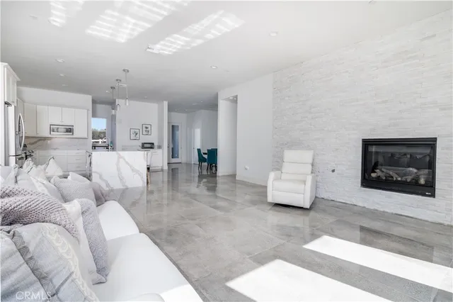 a large dining hall with stainless steel appliances kitchen island granite countertop a table chairs and a view of living room