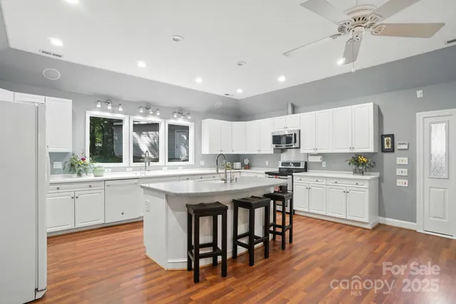 a kitchen with center island wooden floor and stainless steel appliances
