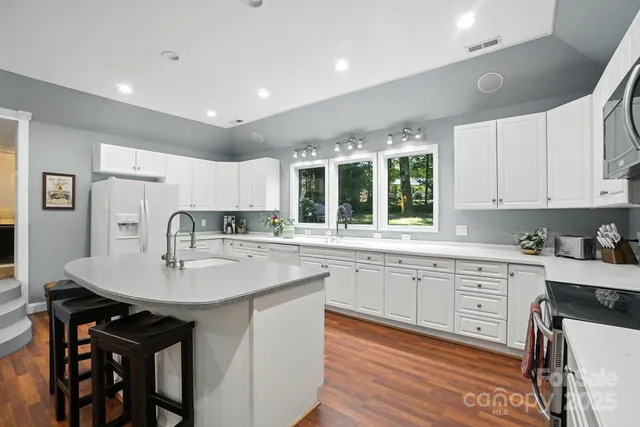 a kitchen with granite countertop white cabinets and chairs