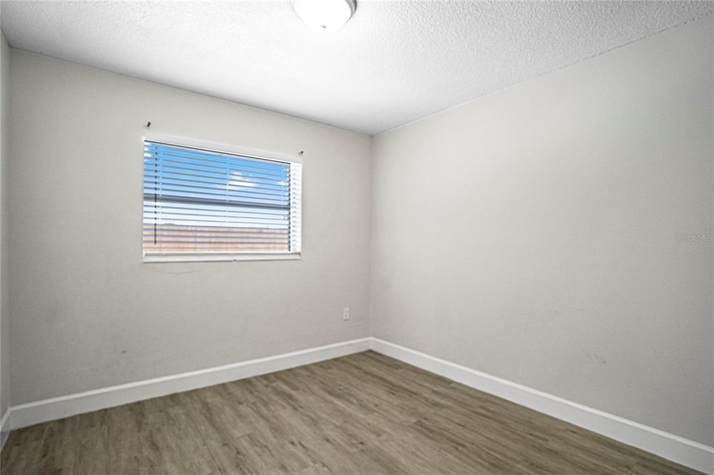 4138 Westgate Road Orlando, FL 32808 - Photo 19 of 29 a view of an empty room with wooden floor and a window