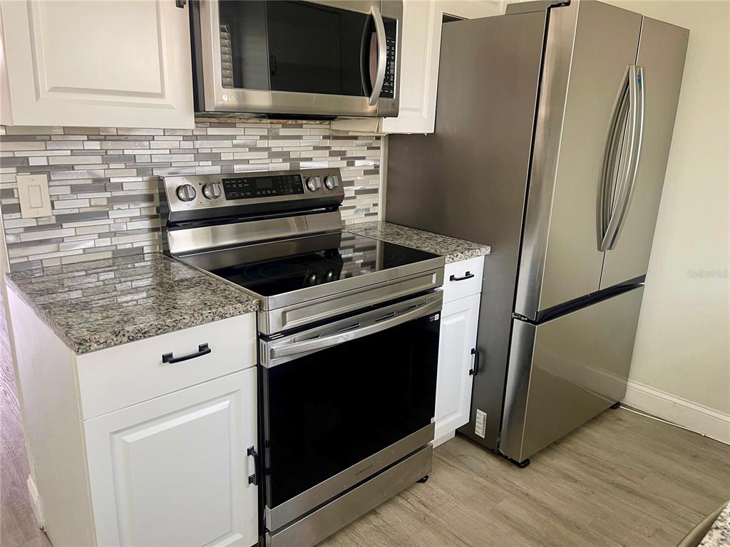 4138 Westgate Road Orlando, FL 32808 - Photo 3 of 29 a kitchen with granite countertop a stove microwave and refrigerator