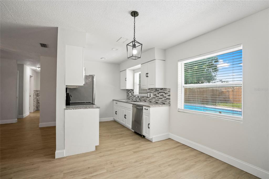 4138 Westgate Road Orlando, FL 32808 - Photo 6 of 29 a kitchen with stainless steel appliances granite countertop a sink dishwasher a refrigerator and a fireplace with wooden floor