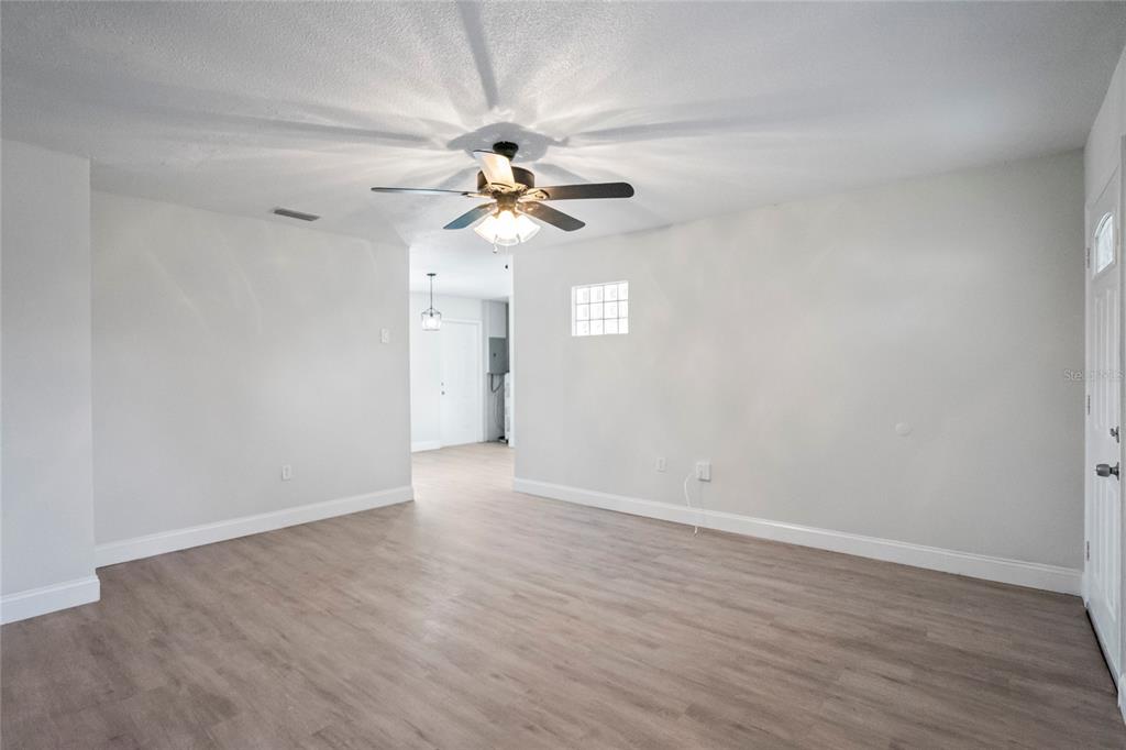 4138 Westgate Road Orlando, FL 32808 - Photo 9 of 29 a view of a big room with wooden floor a ceiling fan and window