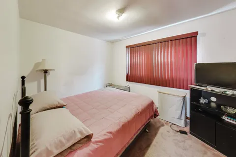 a bedroom with a bed and a flat tv screen on the dresser