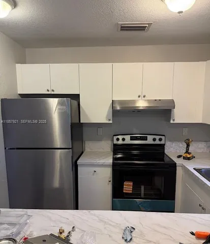 a kitchen with a refrigerator stove and white cabinets