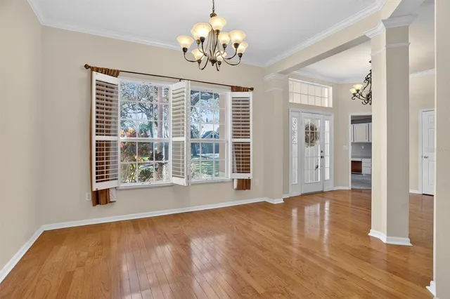 a view of an empty room with a window and wooden floor