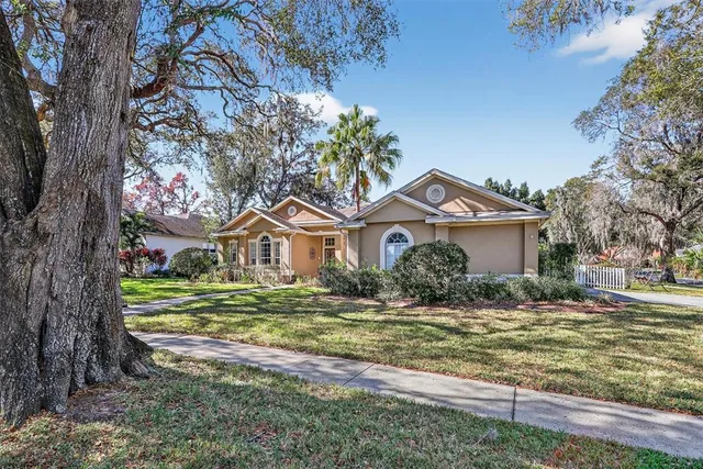 a front view of a house with a yard and large trees