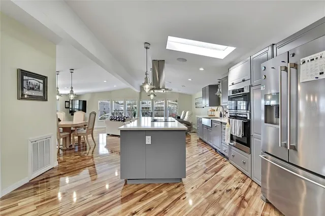 a kitchen with stainless steel appliances a refrigerator a stove a sink dishwasher with a dining table and chairs