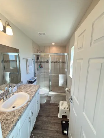 a bathroom with a granite countertop sink a mirror and a shower