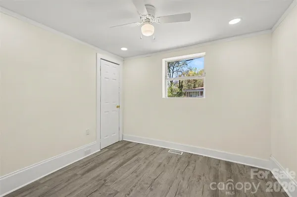 an empty room with wooden floor ceiling fan and windows