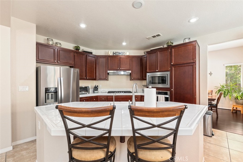 46123 Drymen Avenue Temecula, CA 92592 - Photo 18 of 42 a kitchen with granite countertop a refrigerator stove microwave and cabinets
